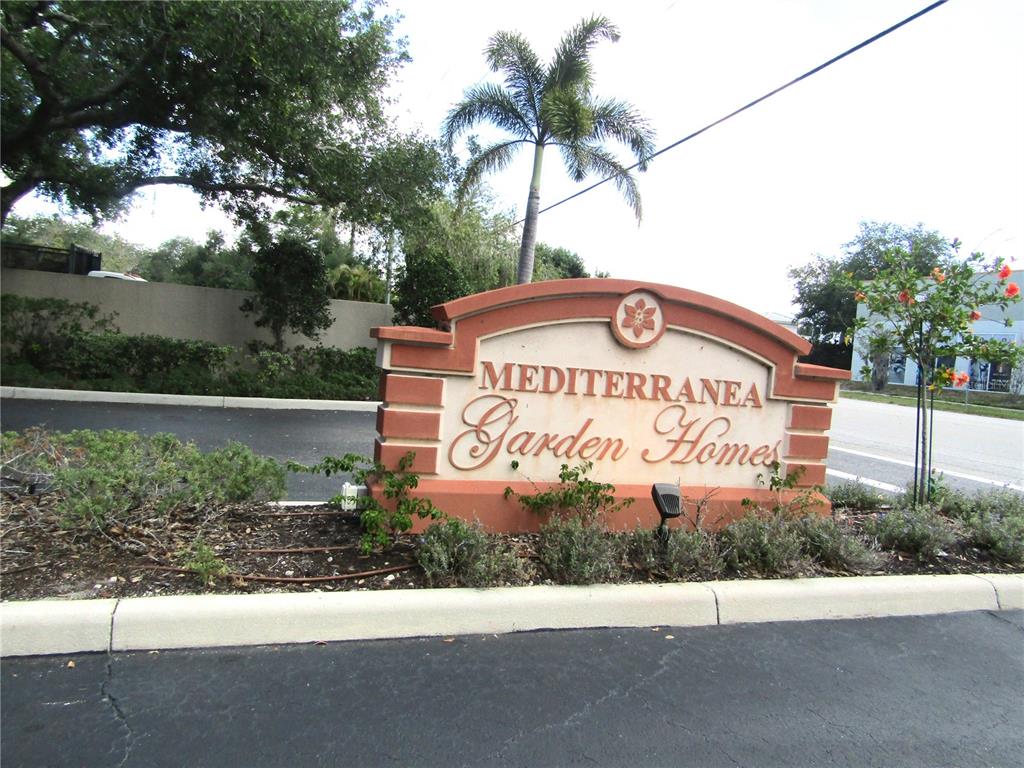 A monument sign for Mediterranea Garden Homes stands at the entrance of a residential community — 3966 MEDITERRANEA CIRCLE UNIT 421, SARASOTA, FL