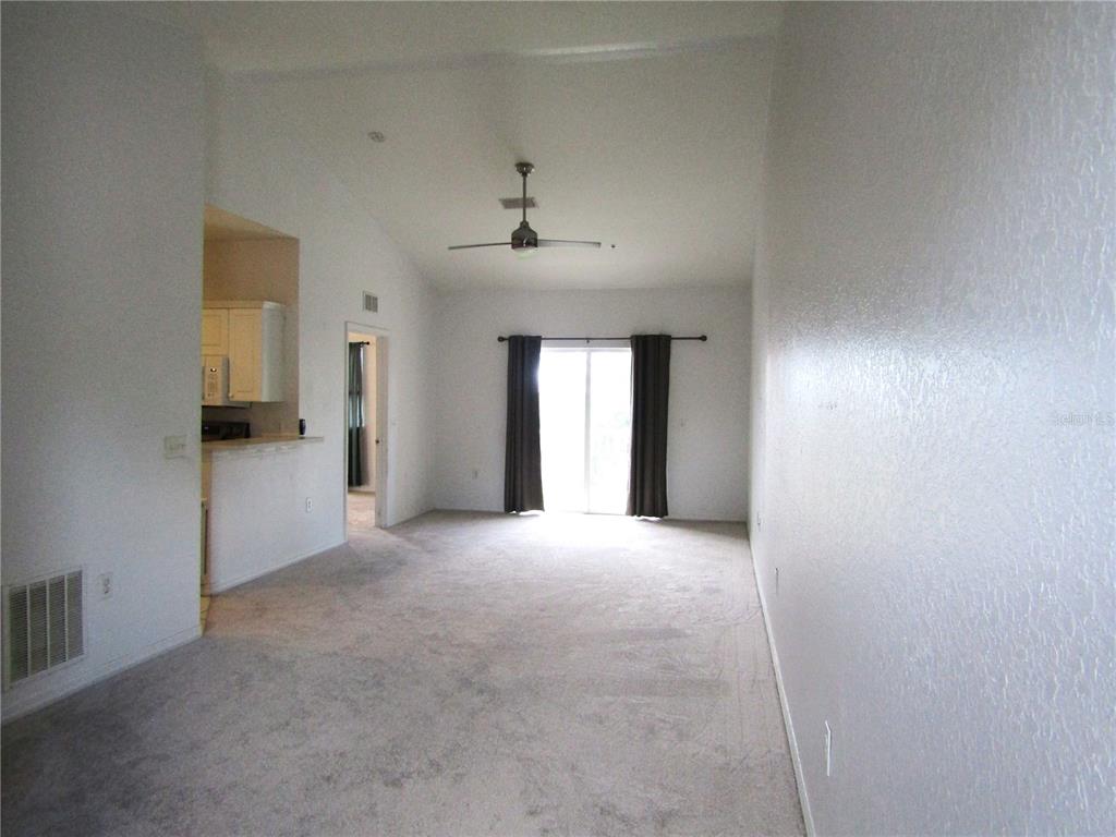 A living room with carpeted floors, a ceiling fan, and a sliding glass door — 3966 MEDITERRANEA CIRCLE UNIT 421, SARASOTA, FL