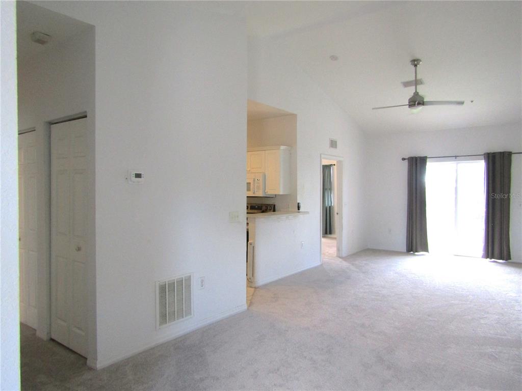 A living room with carpeted floors, a ceiling fan, and an adjacent kitchen area — 3966 MEDITERRANEA CIRCLE UNIT 421, SARASOTA, FL