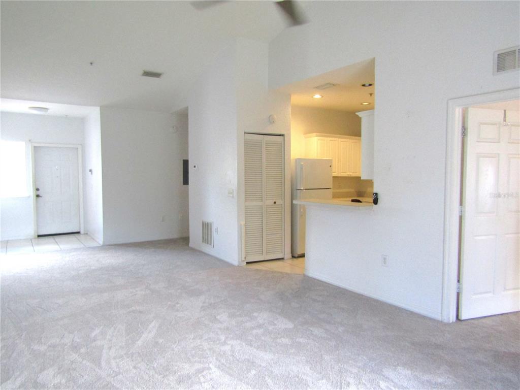 A carpeted living room opens to a kitchen with white cabinets and a breakfast bar — 3966 MEDITERRANEA CIRCLE UNIT 421, SARASOTA, FL