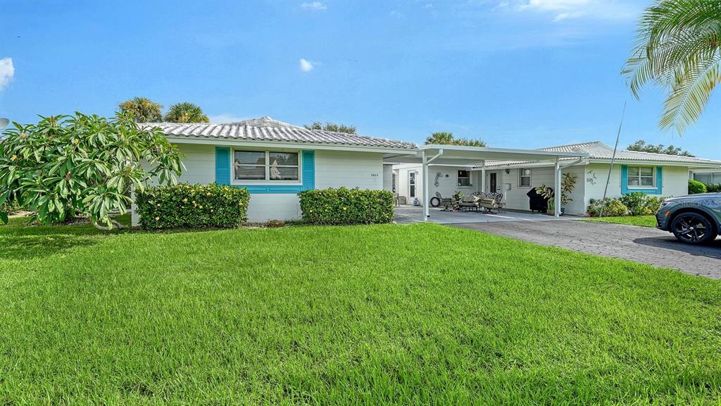 A single-story house with a white exterior, blue shutters, and a covered carport — 1523 LAKESIDE DRIVE UNIT 15, VENICE, FL