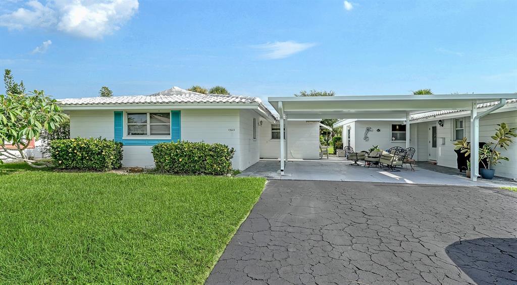 A single-story white house with a carport, a paved driveway, and a green lawn — 1523 LAKESIDE DRIVE UNIT 15, VENICE, FL
