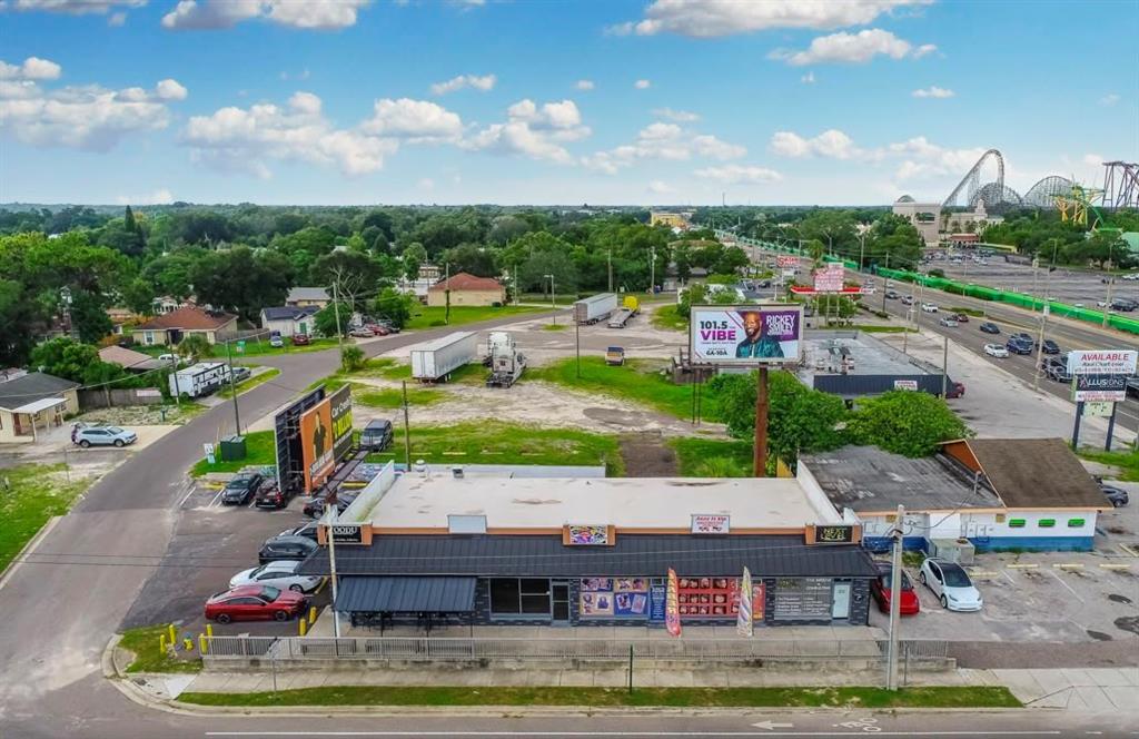 An aerial view shows a commercial building with a parking lot and nearby billboards — 9002 N 40TH, TAMPA, FL