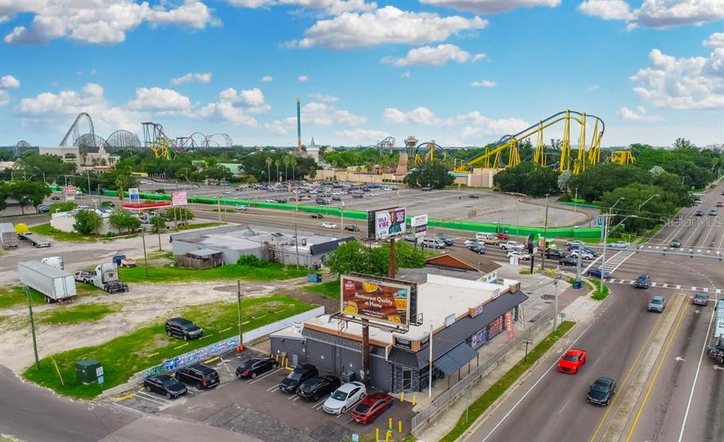 An aerial view shows a commercial building with a parking lot near a theme park — 9002 N 40TH, TAMPA, FL