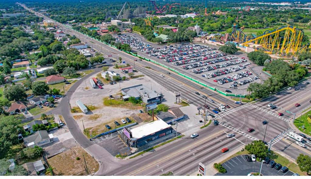 An aerial view shows a commercial property, a large parking lot, and nearby amusement park rides — 9002 N 40TH, TAMPA, FL