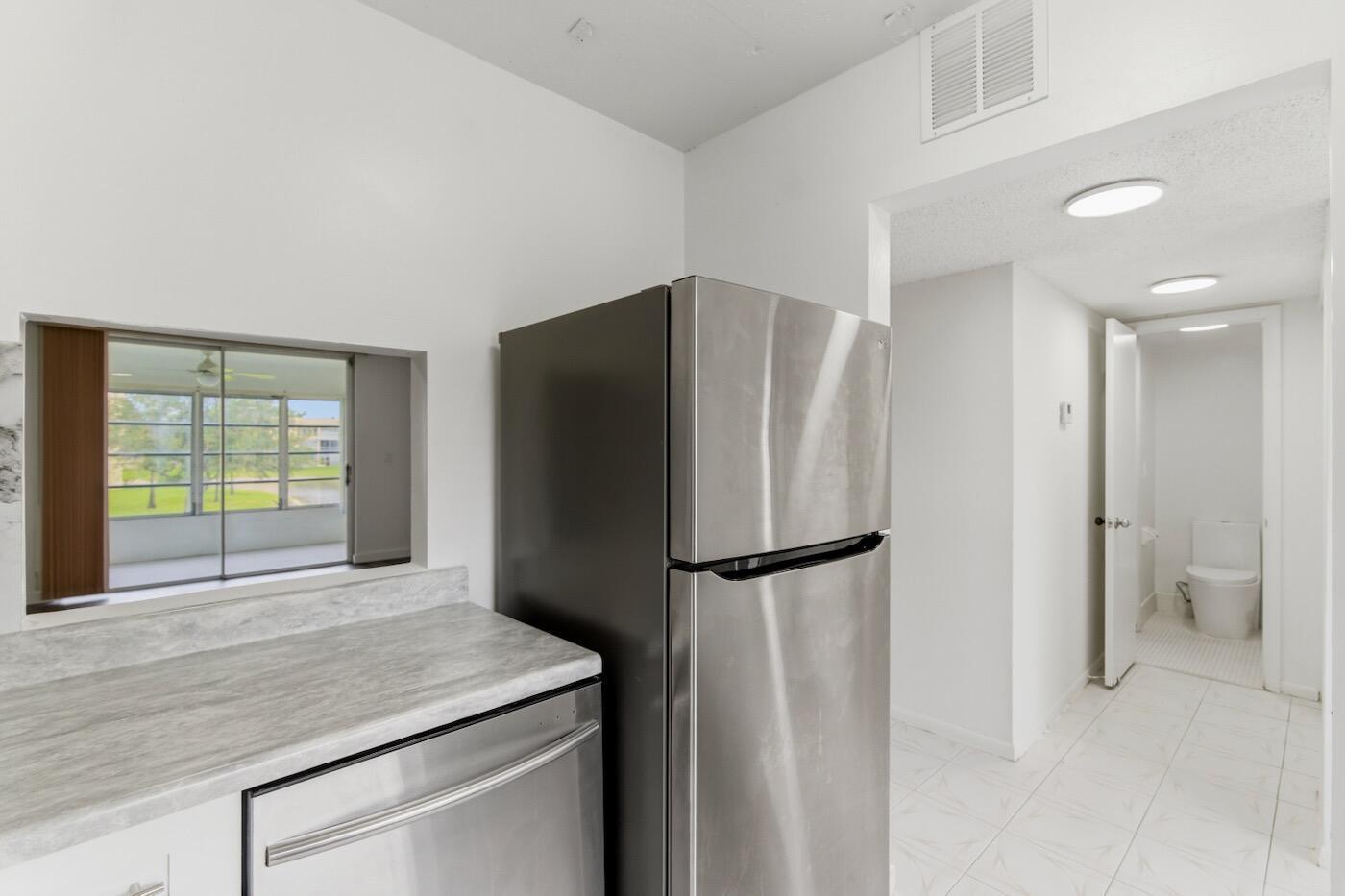 A kitchen with stainless steel appliances and a pass-through window looking into a sunroom — 6020 NW 64th Avenue # 208, Tamarac FL 33319, TAMARAC, FL