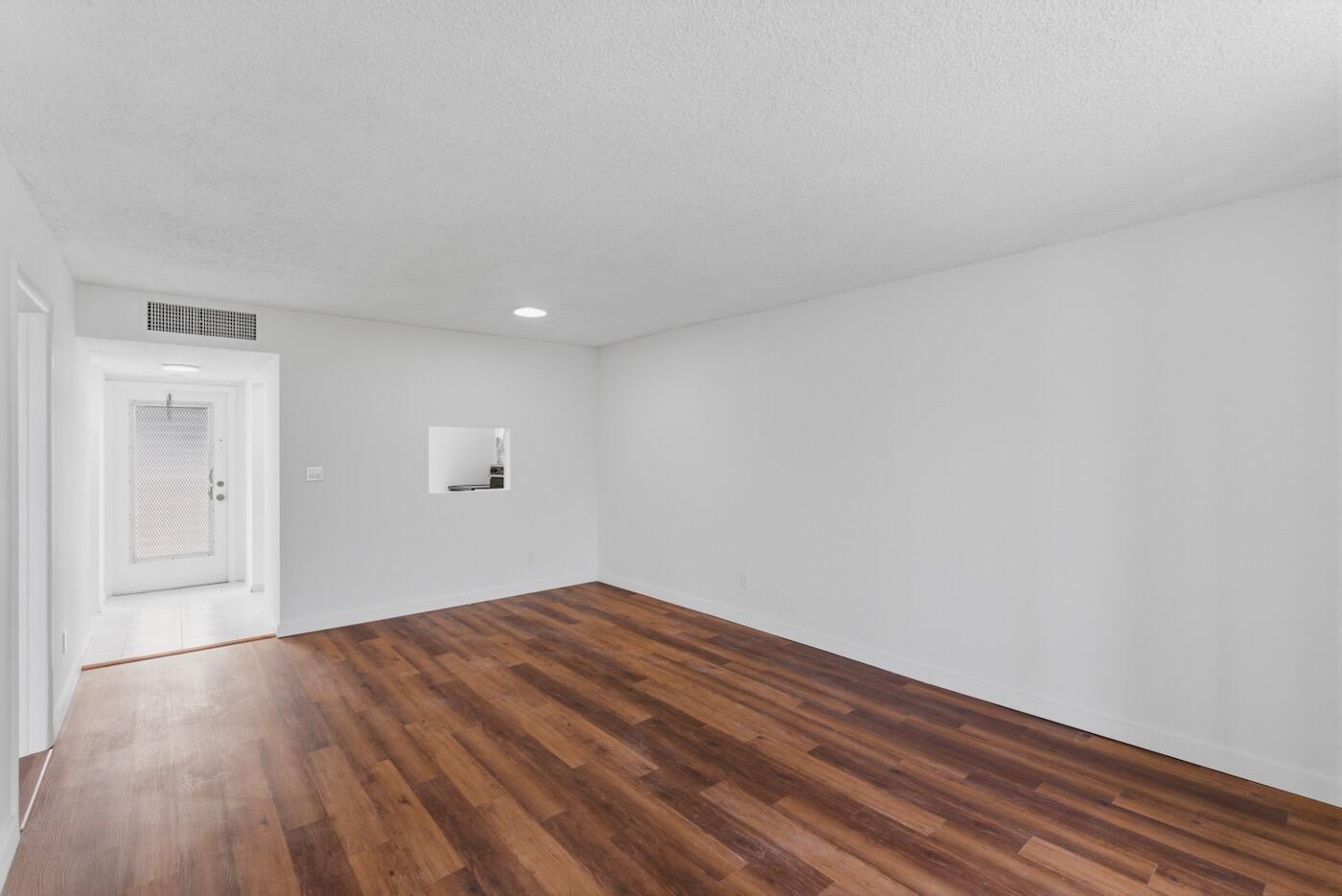 An empty room with white walls, wood-look flooring, and a doorway leading to an entryway — 6020 NW 64th Avenue # 208, Tamarac FL 33319, TAMARAC, FL