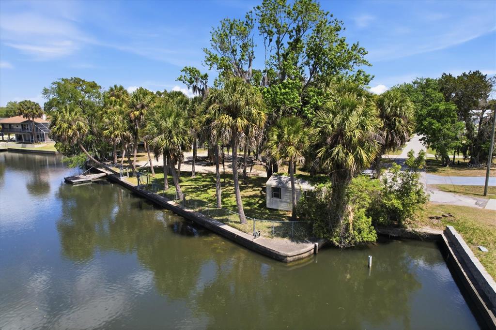 An aerial view of a waterfront lot featuring palm trees, a small shed, and a seawall — 1941 NW 16TH STREET, CRYSTAL RIVER, FL