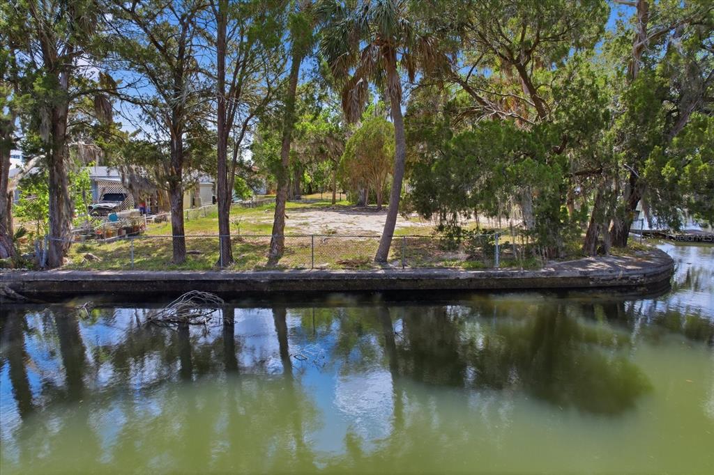 A vacant waterfront lot features a concrete seawall, a chain-link fence, and several mature trees — 1941 NW 16TH STREET, CRYSTAL RIVER, FL