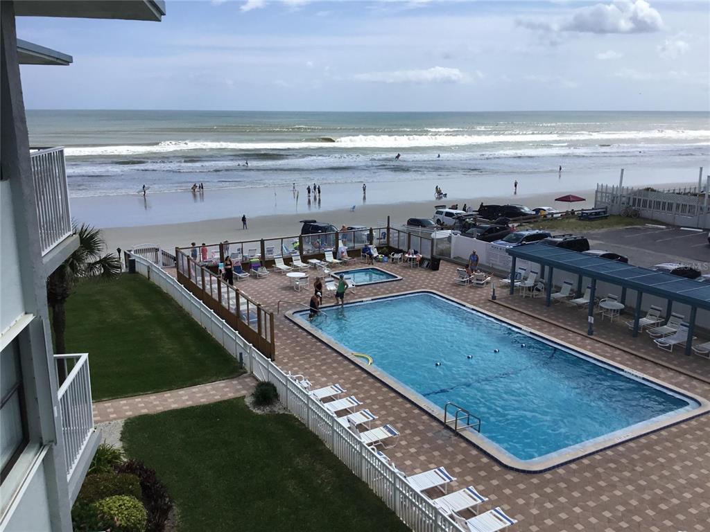An elevated view of a swimming pool, hot tub, and beach with the ocean beyond — 1571 S ATLANTIC AVENUE UNIT 406, NEW SMYRNA BEACH, FL