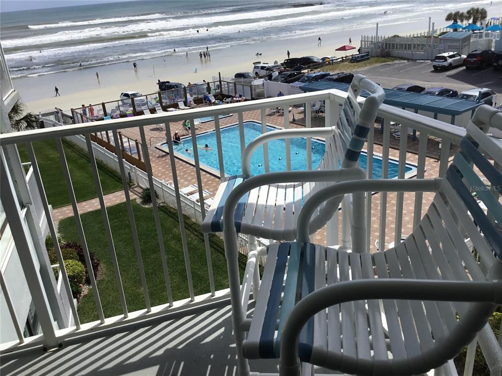 A balcony view overlooks a swimming pool, a parking lot, and the beach — 1571 S ATLANTIC AVENUE UNIT 406, NEW SMYRNA BEACH, FL