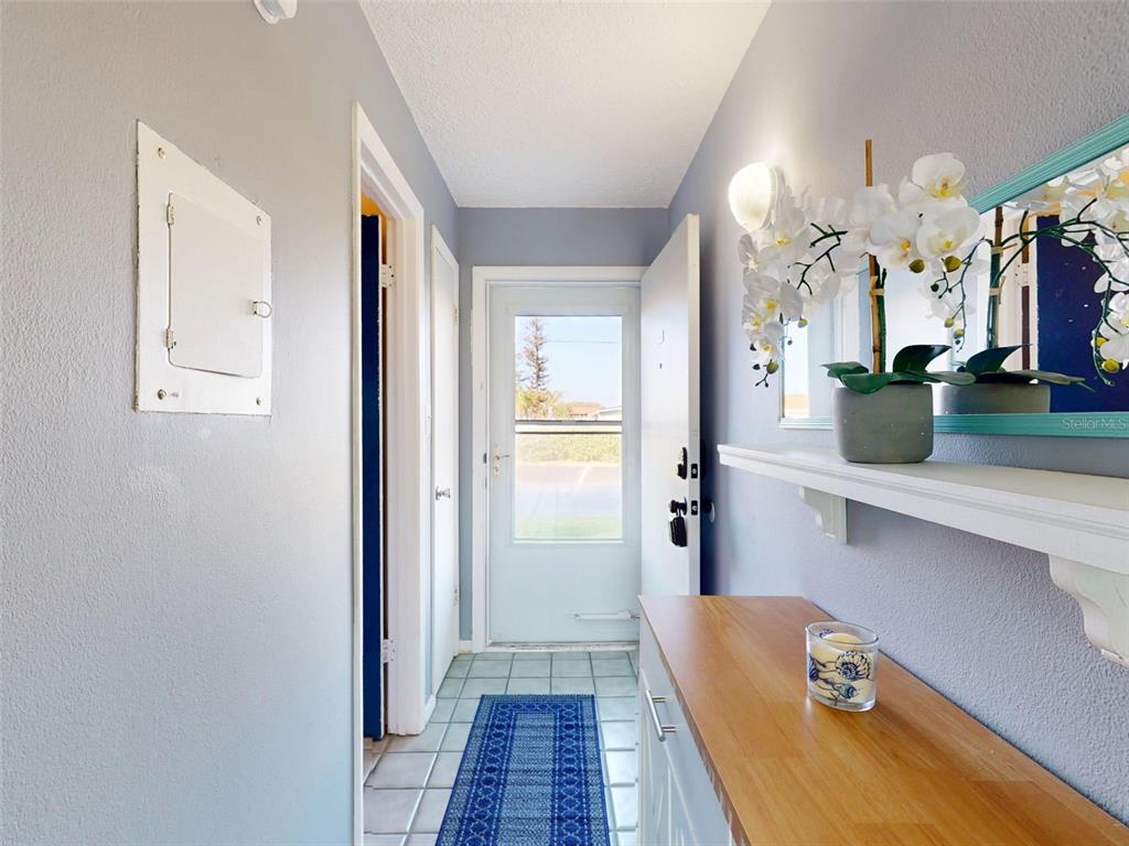 A hallway features light gray walls, a tiled floor with a runner, and a wooden console — 3700 S ATLANTIC AVENUE UNIT 103, NEW SMYRNA BEACH, FL