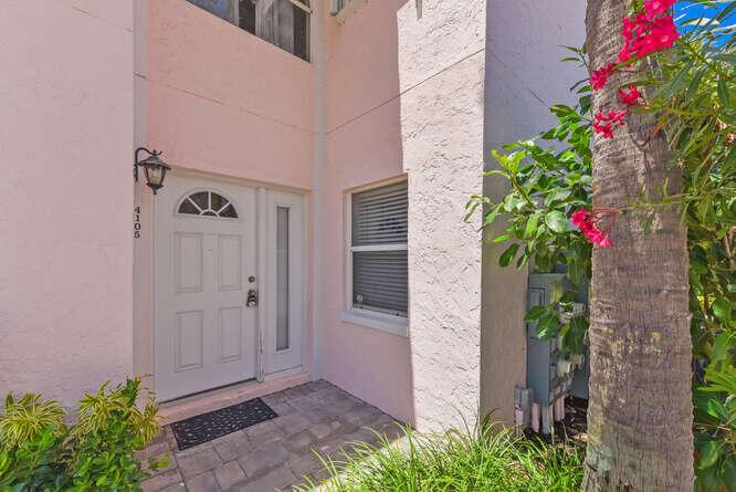 The exterior entrance of a pink stucco building features a white front door and window — 4105 FAIRWAY Drive N, Jupiter FL 33477, JUPITER, FL