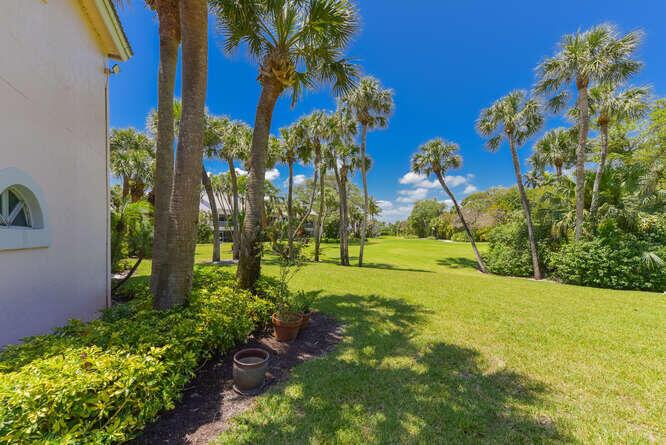 A view of a grassy lawn with palm trees next to a residential building — 4105 FAIRWAY Drive N, Jupiter FL 33477, JUPITER, FL