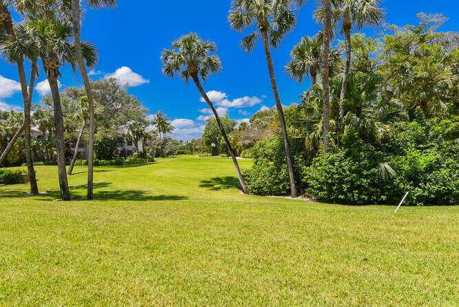 A grassy golf course fairway is lined with tall palm trees under a blue sky — 4105 FAIRWAY Drive N, Jupiter FL 33477, JUPITER, FL