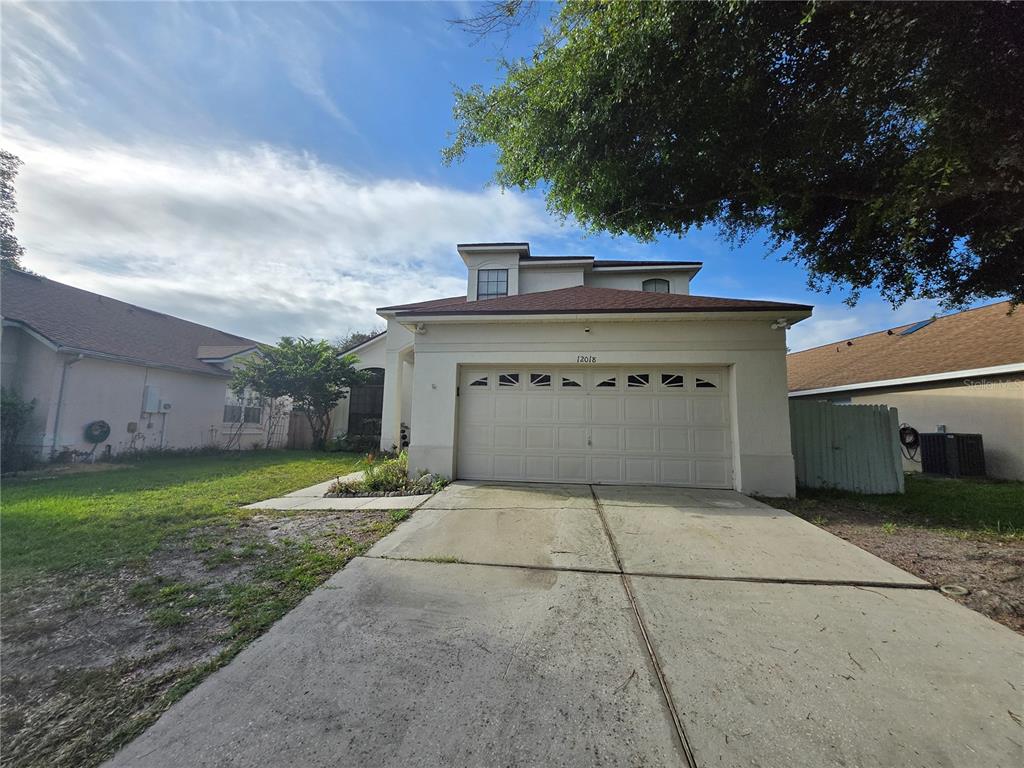 A two-story house with a beige stucco exterior and a two-car garage — 12018 GRECO, ORLANDO, FL