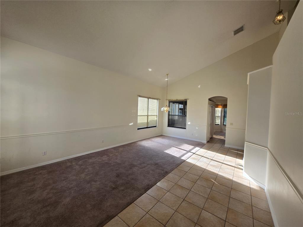 A living room features carpeted flooring, tile near the entrance, and a vaulted ceiling — 12018 GRECO, ORLANDO, FL