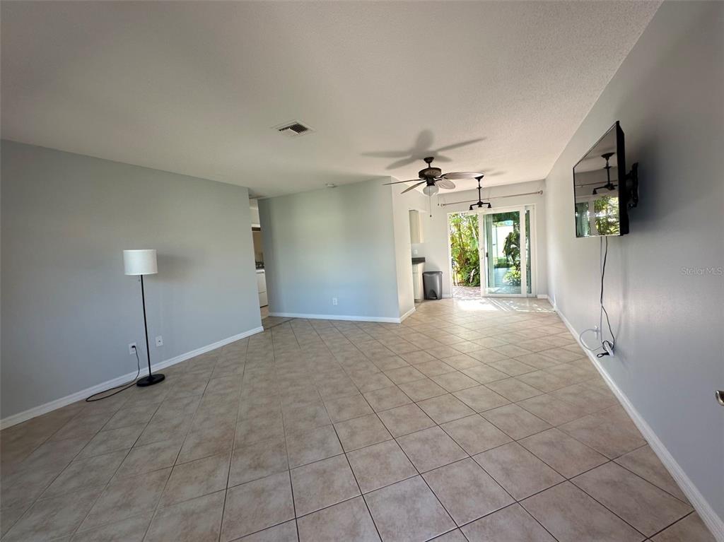 An empty living room features light gray walls, diagonal tile flooring, a ceiling fan, and sliding doors — 2105 PUEBLO CIRCLE UNIT V2, SARASOTA, FL