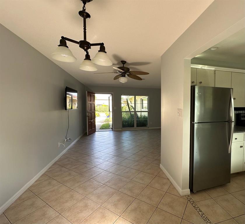 A tiled dining area features a chandelier, ceiling fan, and a view of the outdoors — 2105 PUEBLO CIRCLE UNIT V2, SARASOTA, FL