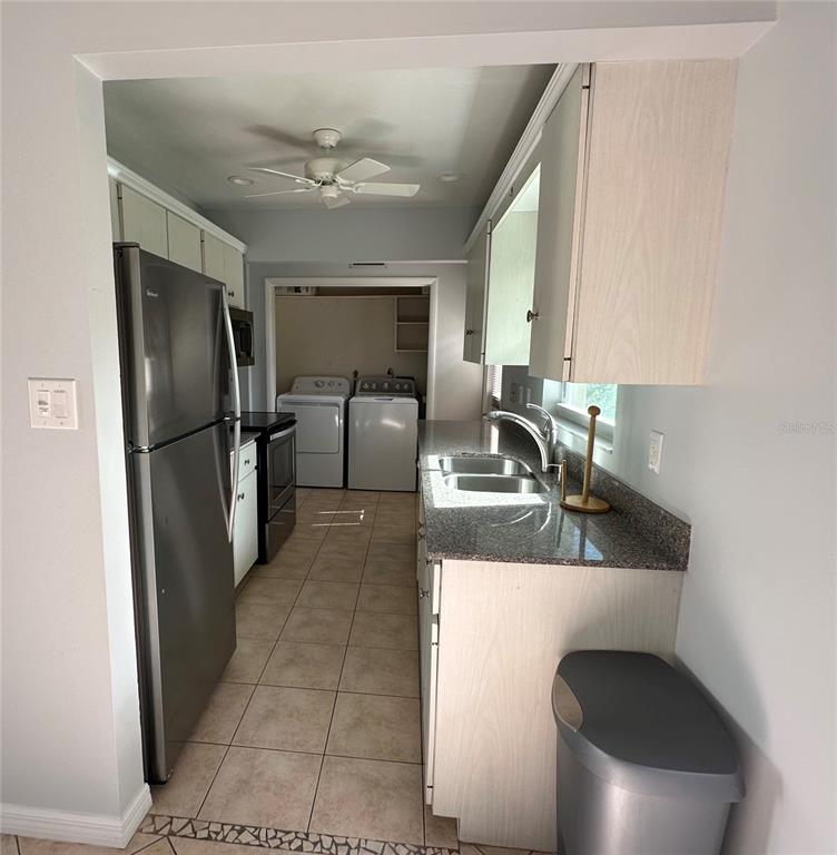 A kitchen with stainless steel appliances, granite countertops, and an adjacent laundry area — 2105 PUEBLO CIRCLE UNIT V2, SARASOTA, FL