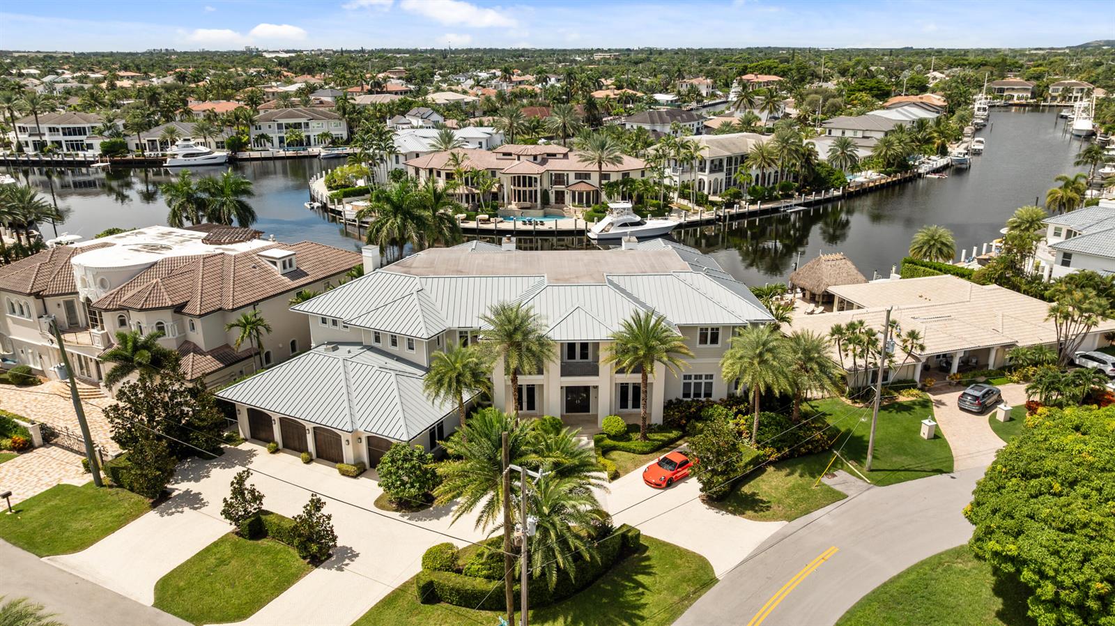 An aerial view of a large waterfront mansion with a metal roof and orange car — 3211 NE 27th Avenue, Lighthouse Point FL 33064, LIGHTHOUSE POINT, FL