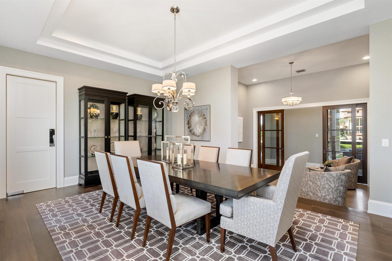 A dining room features a dark wood table, upholstered chairs, a chandelier, and glass cabinets — 3211 NE 27th Avenue, Lighthouse Point FL 33064, LIGHTHOUSE POINT, FL