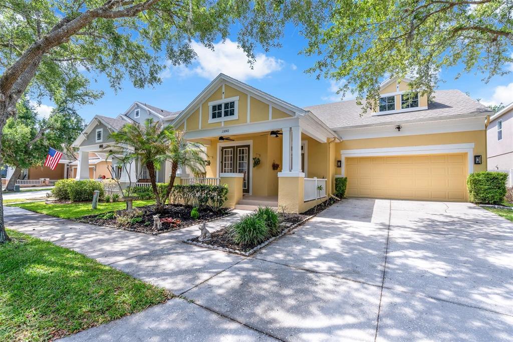 A yellow single-story house with a front porch, attached garage, and a landscaped front yard — 13842 ORANGE CREST DRIVE, WINDERMERE, FL