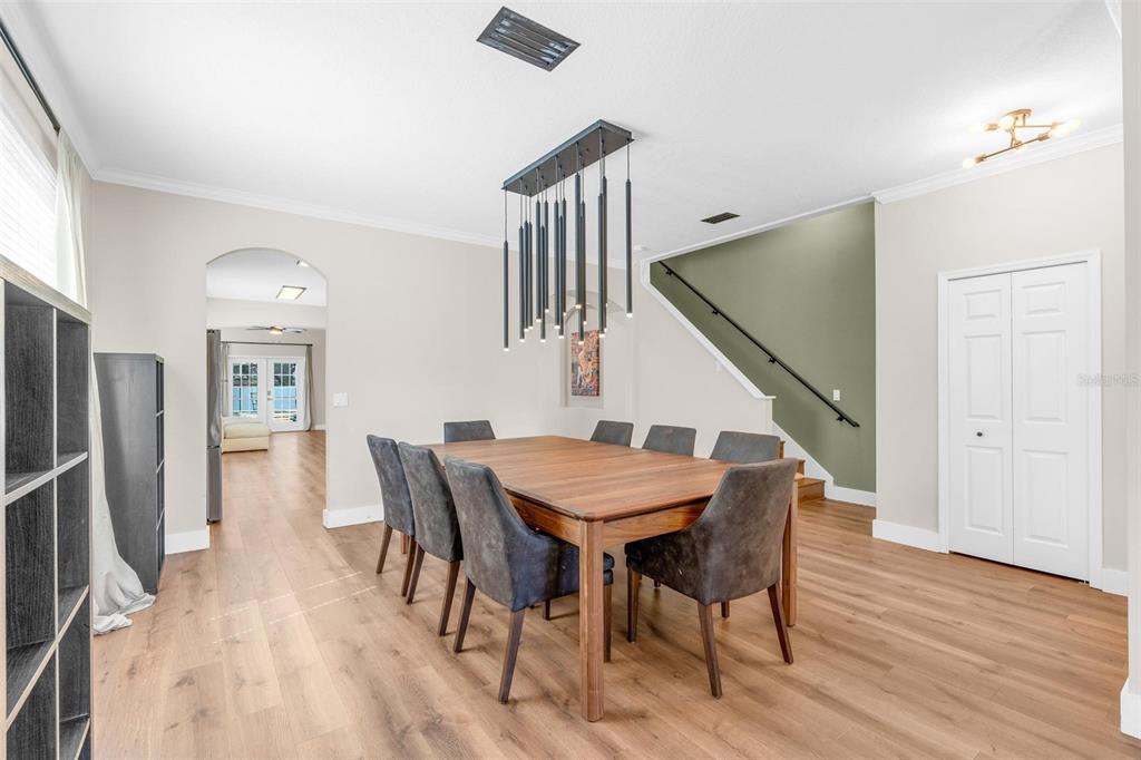 A dining room features a wooden table, dark chairs, a modern pendant light, and stairs — 13842 ORANGE CREST DRIVE, WINDERMERE, FL