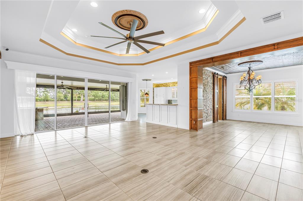 A spacious living room features tile floors, a tray ceiling with a fan, and sliding doors — 15939 CAPE CORAL DRIVE, WIMAUMA, FL