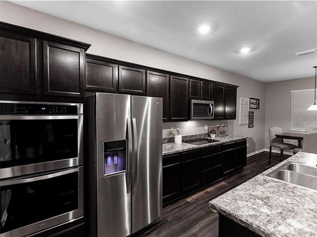 A kitchen features dark wood cabinets, stainless steel appliances, and granite countertops — 9318 EQUITY LANE, SEFFNER, FL