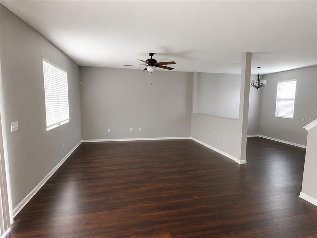 An empty living room features dark wood-look flooring, gray walls, and a ceiling fan — 9318 EQUITY LANE, SEFFNER, FL