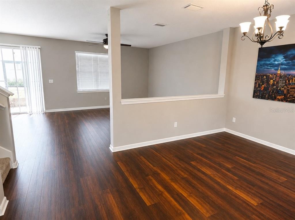 A living area with dark wood flooring, a half wall, and a city skyline painting — 9318 EQUITY LANE, SEFFNER, FL