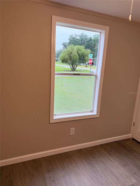 An interior room with light-colored walls, wood-look flooring, and a window overlooking a street — 9195 SE 142ND PLACE, SUMMERFIELD, FL