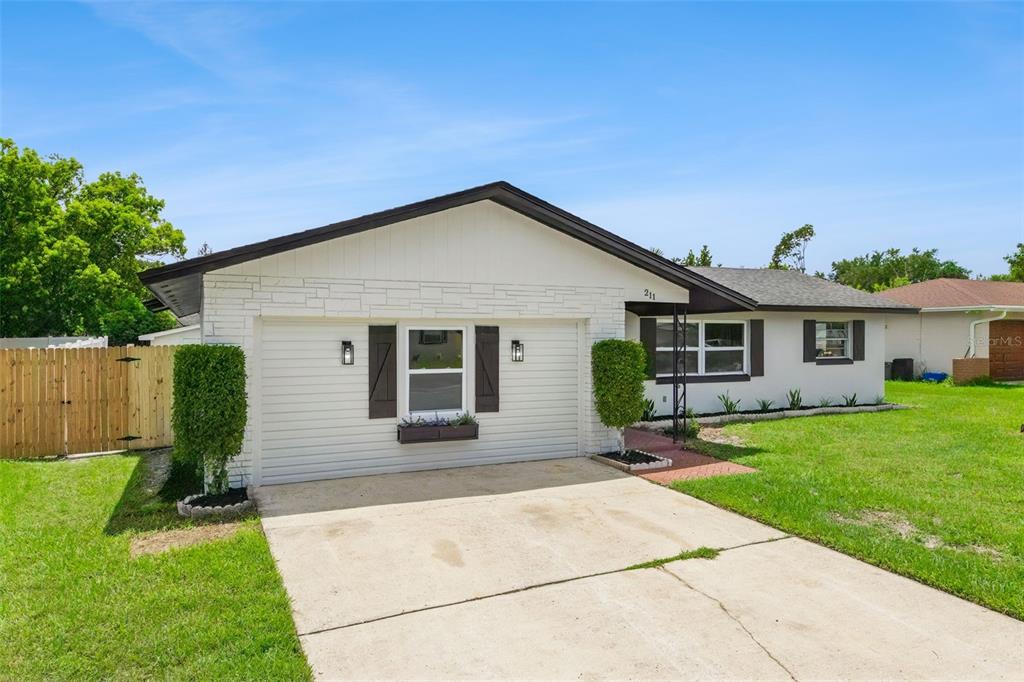 A single-story house features a white brick facade, a two-car garage, and a concrete driveway — 211 MELISSA COURT, SANFORD, FL