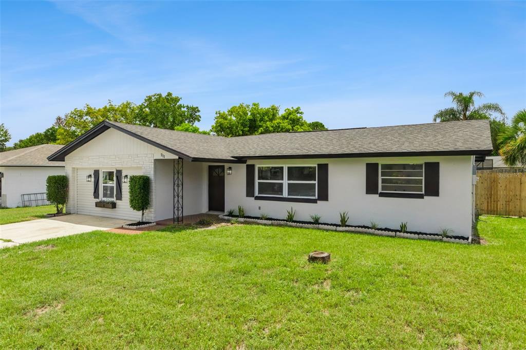 A single-story house with a white exterior, dark shutters, and a front-facing garage — 211 MELISSA COURT, SANFORD, FL
