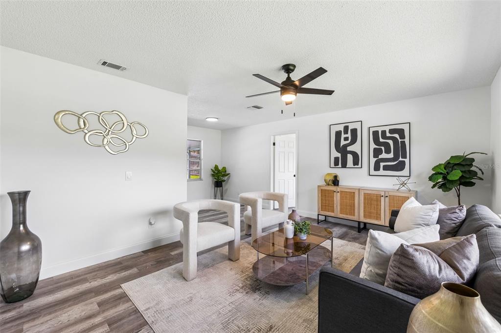 A living room features white walls, wood-look flooring, a ceiling fan, and modern furniture — 211 MELISSA COURT, SANFORD, FL