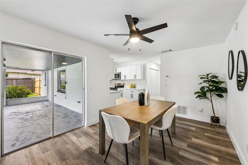 A dining area with a wooden table, white chairs, and a sliding door to a patio — 211 MELISSA COURT, SANFORD, FL