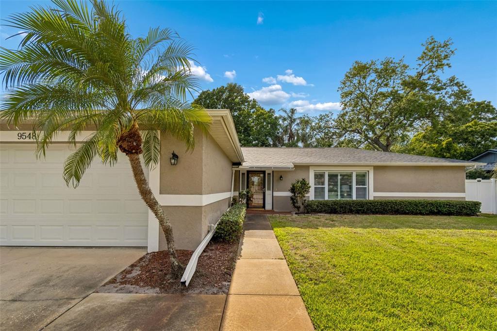 A single-story house with a tan exterior, a palm tree, and a concrete walkway — 9548 123RD WAY N, SEMINOLE, FL