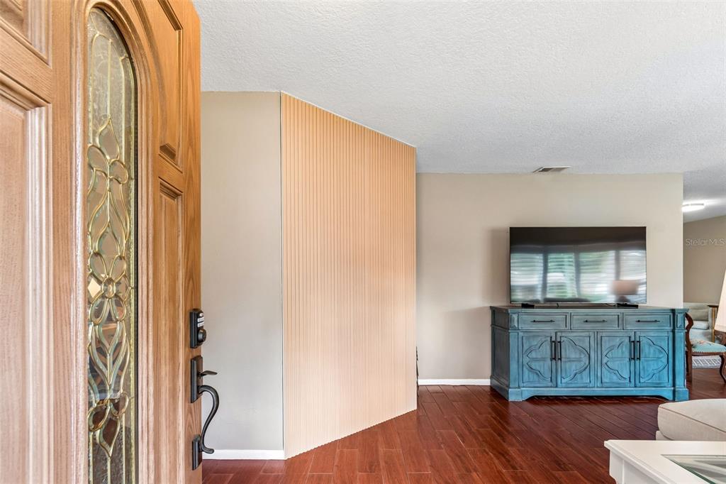 An entryway opens into a living room with wood-look tile floors and a slatted wood wall — 9548 123RD WAY N, SEMINOLE, FL