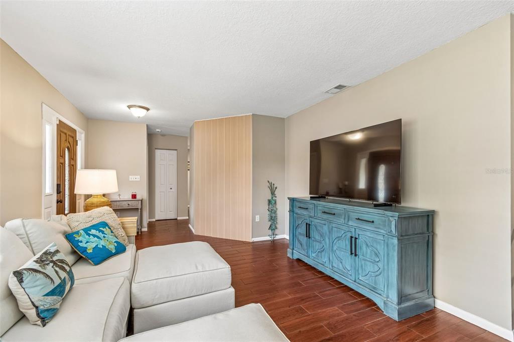 A living room features a white sectional sofa, a blue media console, and wood flooring — 9548 123RD WAY N, SEMINOLE, FL