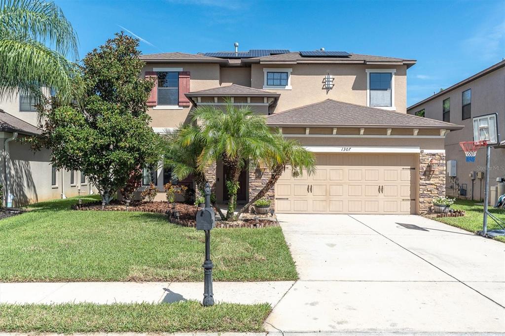 A two-story suburban house features a tan stucco exterior, a stone-accented entryway, and a garage — 1307 KETZAL DRIVE, TRINITY, FL