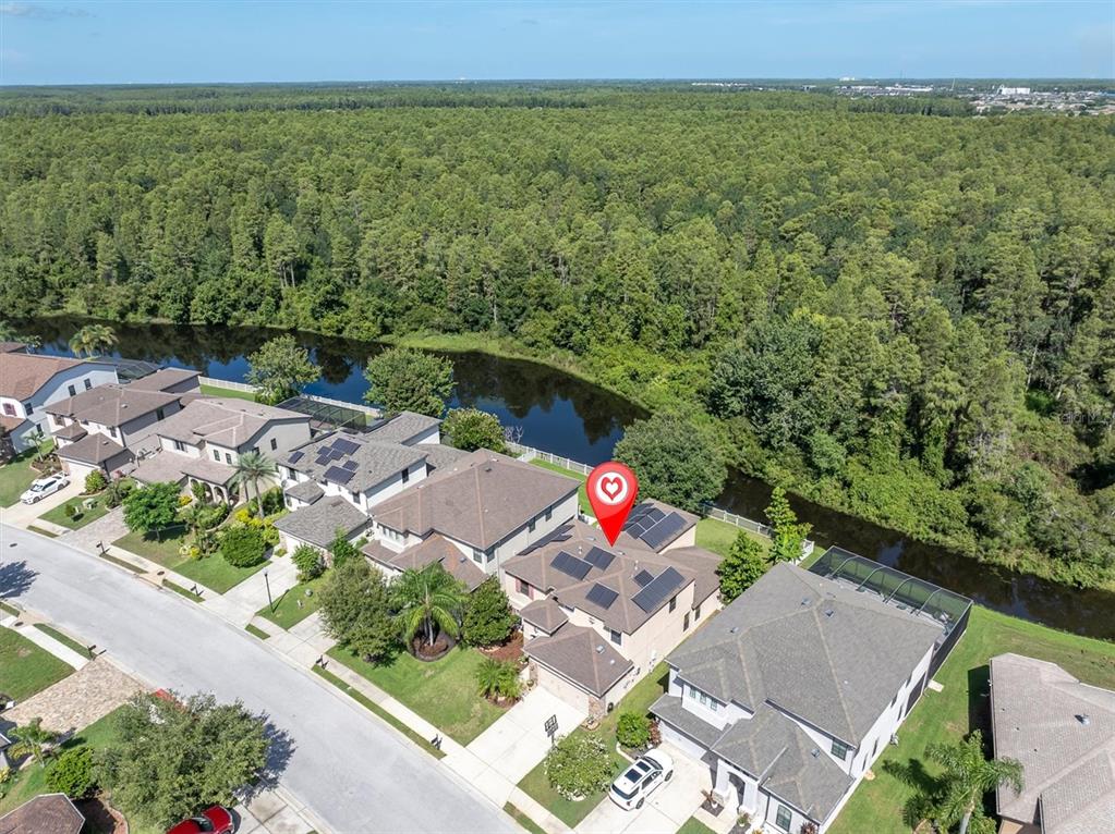 An aerial view shows a suburban house with solar panels next to a canal — 1307 KETZAL DRIVE, TRINITY, FL