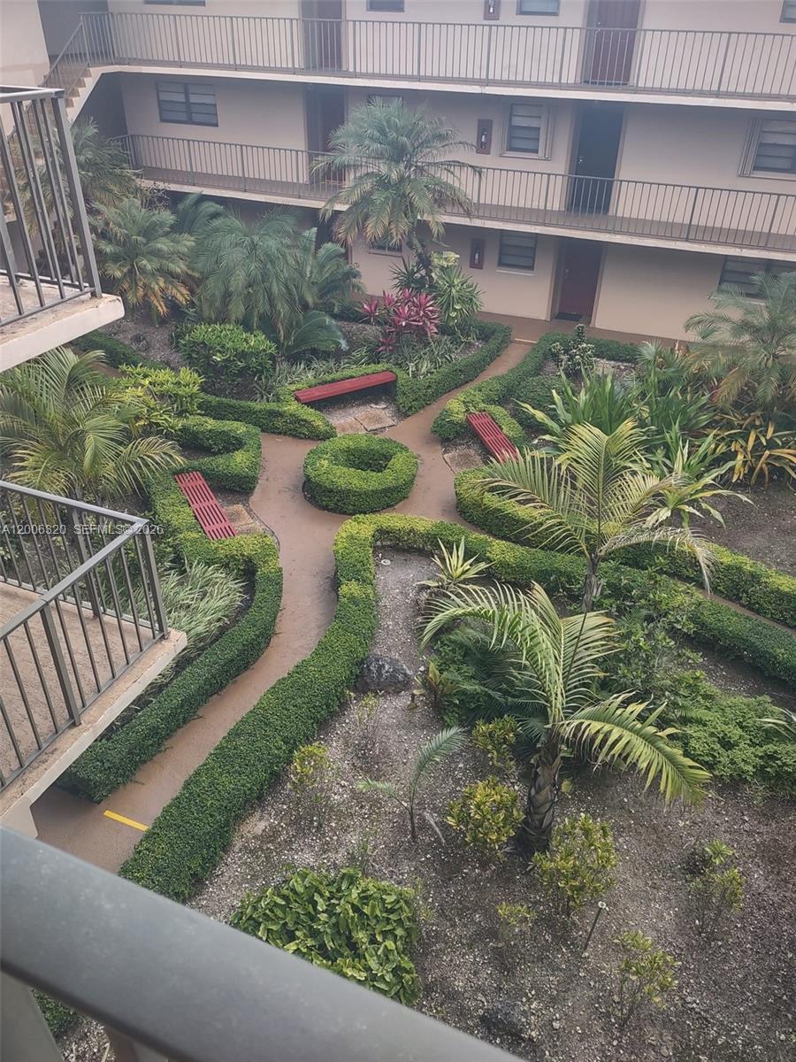 An elevated view of a landscaped courtyard with hedges, palm trees, and benches — 10625 SW 112th Ave # 301, Miami FL 33176, MIAMI, FL