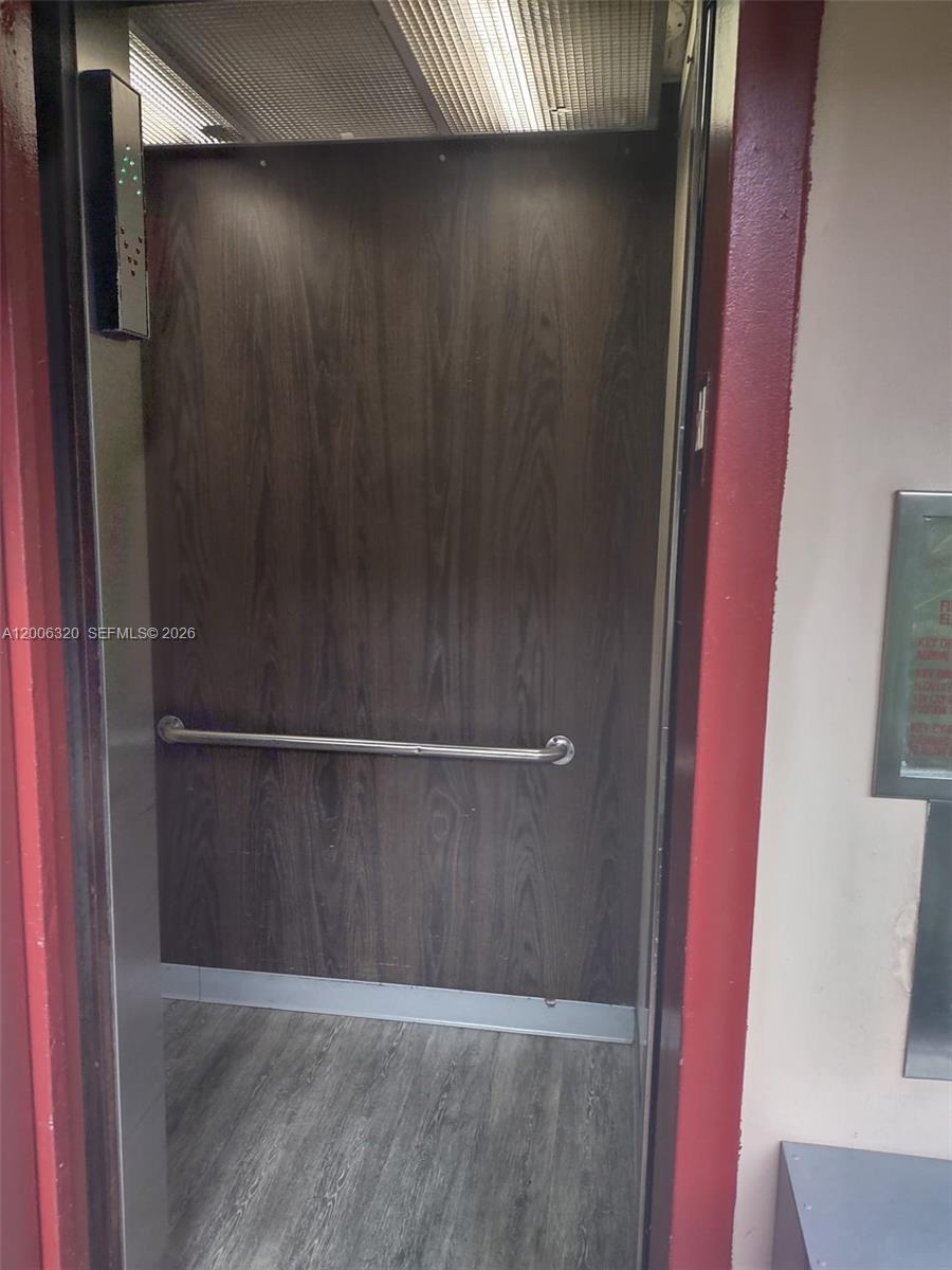 An elevator interior features wood-paneled walls, a metal handrail, and a gray wood-look floor — 10625 SW 112th Ave # 301, Miami FL 33176, MIAMI, FL