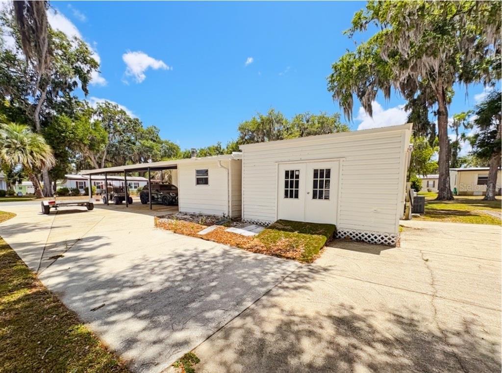 A white exterior home features a double-door entrance, a concrete driveway, and a covered carport — 4 E QUAIL RUN, WILDWOOD, FL