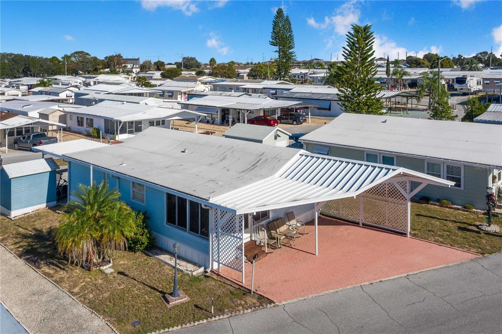 An aerial view of a light blue mobile home with a carport and paved driveway — 251 PATTERSON ROAD UNIT F22, HAINES CITY, FL