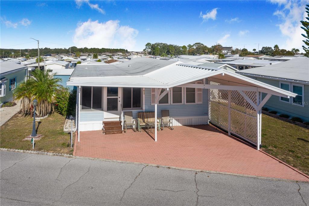 A light blue mobile home features a covered carport and a brick-paved driveway — 251 PATTERSON ROAD UNIT F22, HAINES CITY, FL