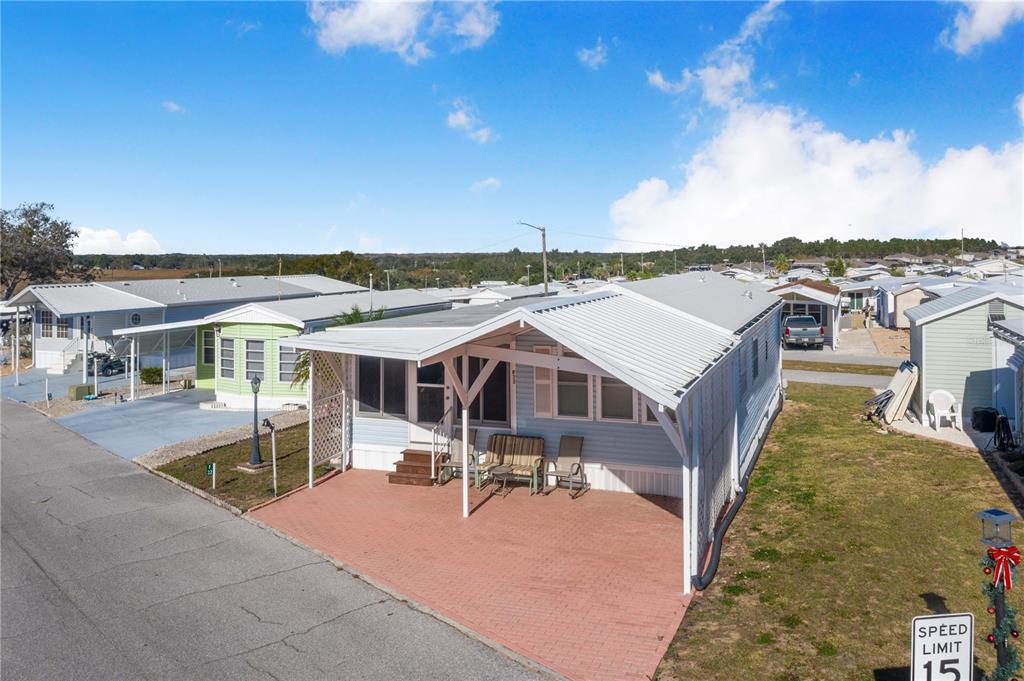 A light blue mobile home with a covered carport and a brick-paved patio area — 251 PATTERSON ROAD UNIT F22, HAINES CITY, FL