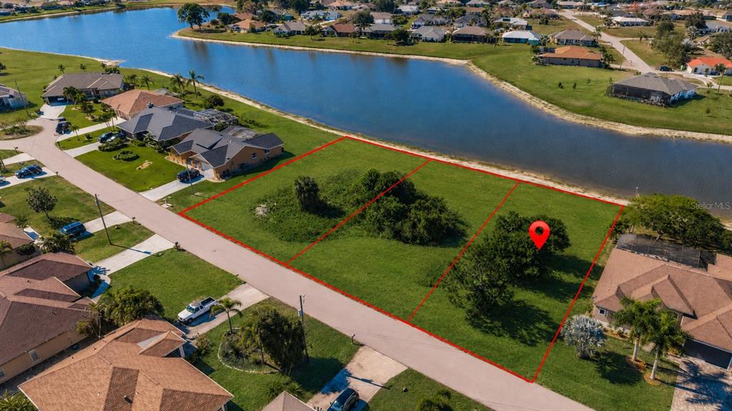 An aerial view shows three vacant, grassy residential lots bordering a lake in a neighborhood — 2369 SOFIA LANE, PUNTA GORDA, FL
