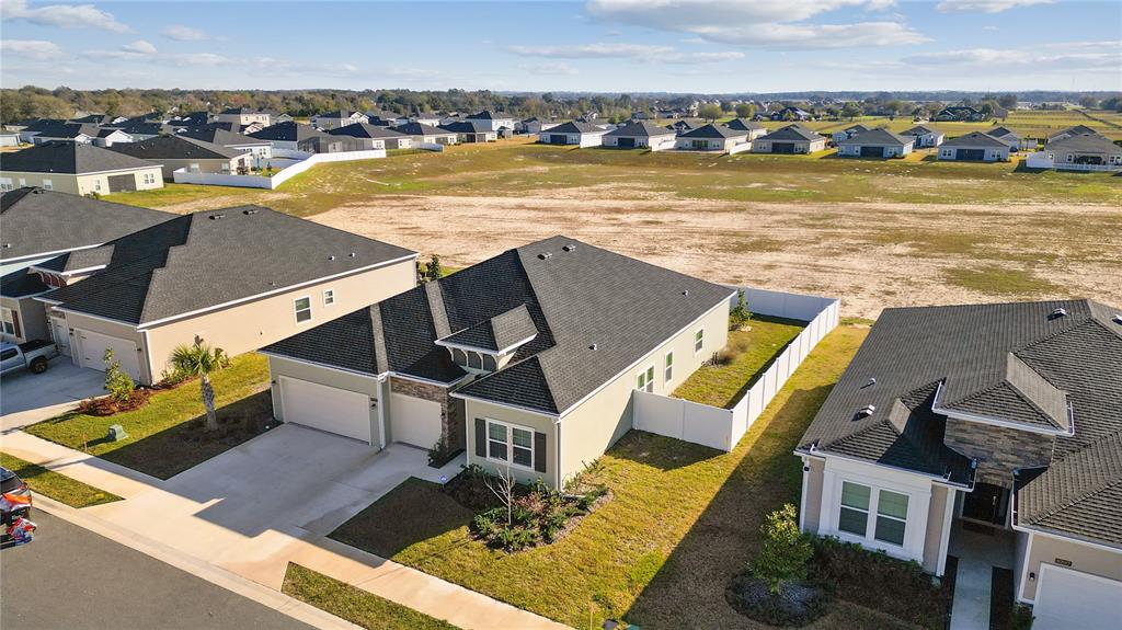 An aerial view shows suburban houses with dark shingled roofs and white vinyl privacy fences — 9191 SW 57TH TERRACE, OCALA, FL